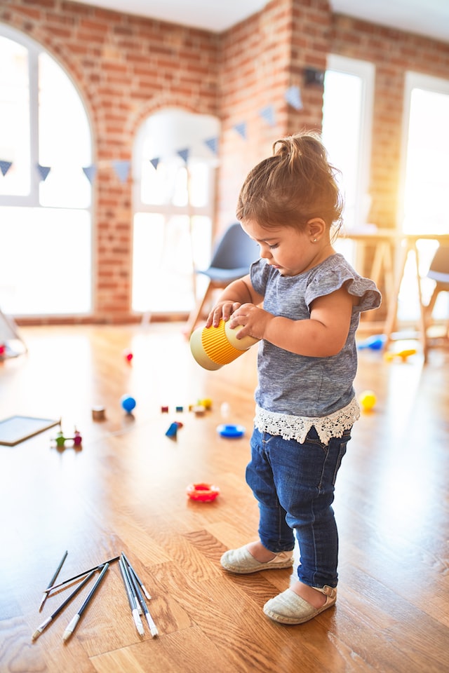 little girl playing with toys in a nursery